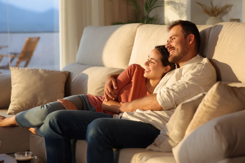 Couple assis sur canapé gris dans salon moderne discutant avec conseiller professionnel tenant documents